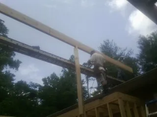 Carpenter setting a ridge beam over a new addition frame — Ice Dam Removal by Roofing Brothers in Eddyville