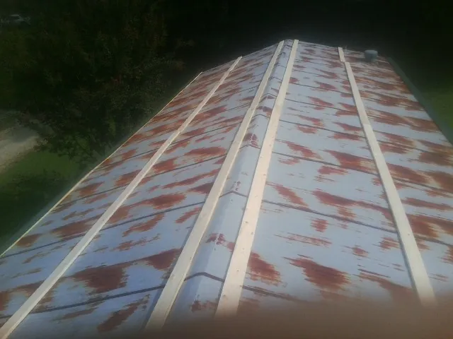Rusted metal roof panels with new wood purlins before replacement — Storm Damage Roof Repair in Eddyville by Roofing Brothers